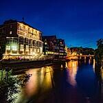 Stimmungsvolle Aufnahme von Lüneburg bei Nacht mit leuchtenden Gebäuden am Flussufer.